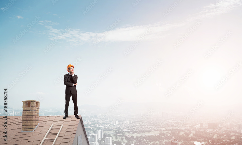 Engineer man standing on roof and looking away. Mixed media Engineer man standing on roof and looking away. Mixed media