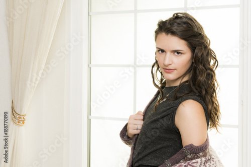 Beautiful, young woman in front of white window