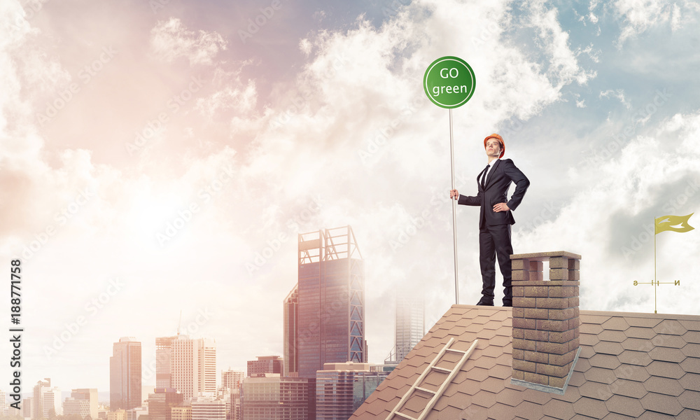Businessman in suit on house top with ecology concept signboard. Businessman in suit on house top with ecology concept signboard.