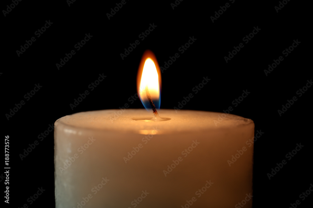 Burning candle on black background, closeup