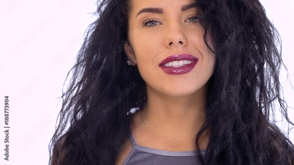 Beautiful brunette with red lips flirts with camera at white background Beautiful brunette with red lips flirts with camera at white background