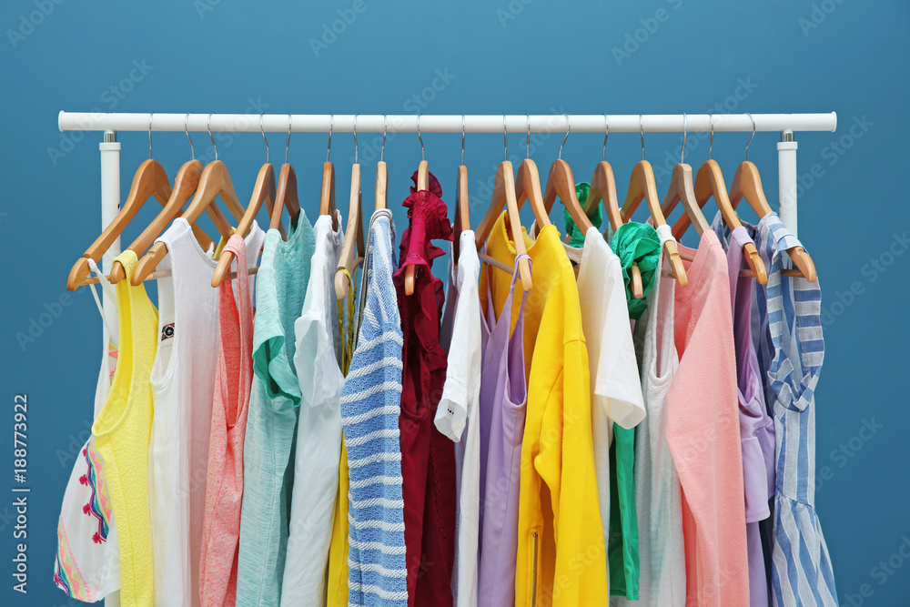 Rack with different clothes near color wall