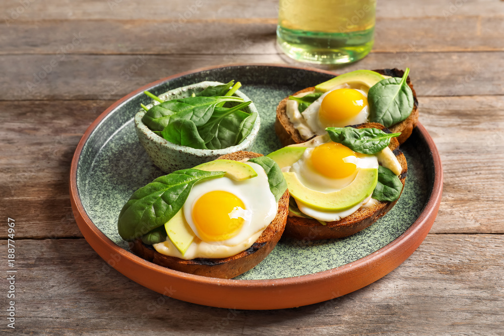 Tasty bruschettas with fried eggs and avocado on plate Tasty bruschettas with fried eggs and avocado on plate