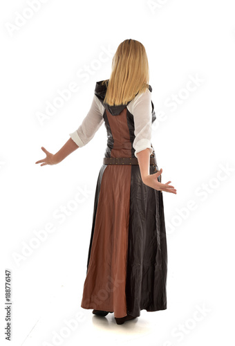 full length portrait of girl wearing brown fantasy costume, standing pose with back to the camera on white studio background. 