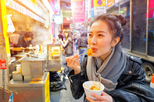 Asian young woman eating Chinese Steamed Dumpling on a street in Hong Kong
