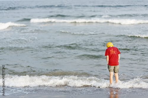 Rear view of boy standing in sea