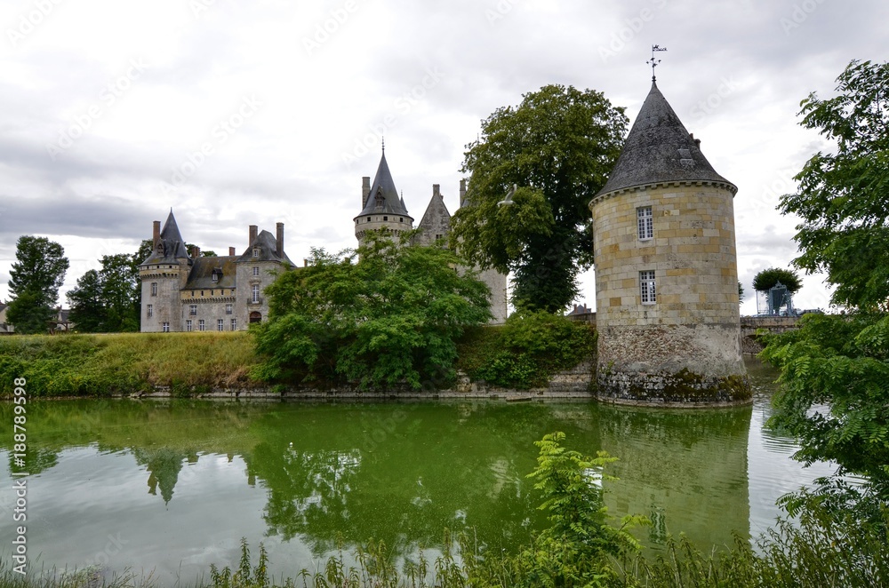 Castle of Sully-sur-Loire, Loire region, France. Snap of 30 June 2017 at 18:21. Captured at the entrance of the castle park. White clouds moving on blue sky. Towers well visible in the image. Castle of Sully-sur-Loire, Loire region, France. Snap of 30 June 2017 at 18:21. Captured at the entrance of the castle park. White clouds moving on blue sky. Towers well visible in the image.