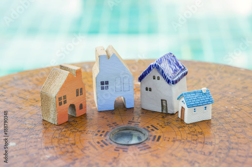 House feng shui concept, beautiful miniature house on ancient wooden feng shui compass over blurred blue water background 
