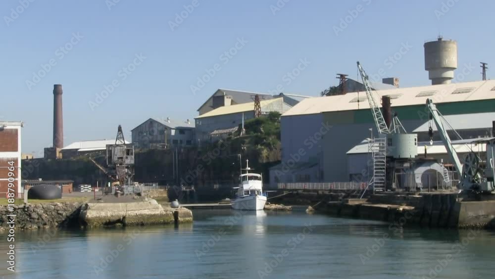 A full shot of a boat and houses with cranes and pier. A full shot of a boat and houses with cranes and pier.