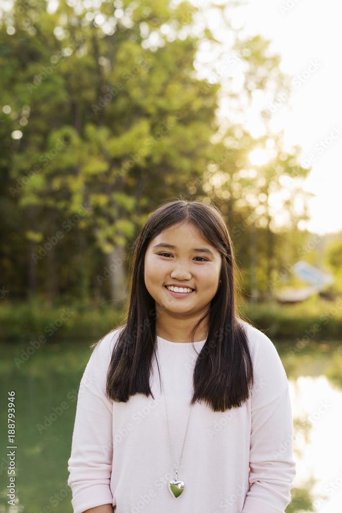 Portrait of smiling girl with straight black hairåÊstanding outdoors Portrait of smiling girl with straight black hairåÊstanding outdoors