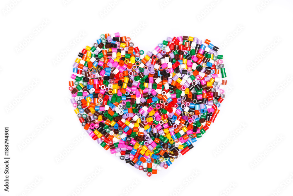 Frame in the shape of hearts. Background of multicolored decorative plastic craft beads. 