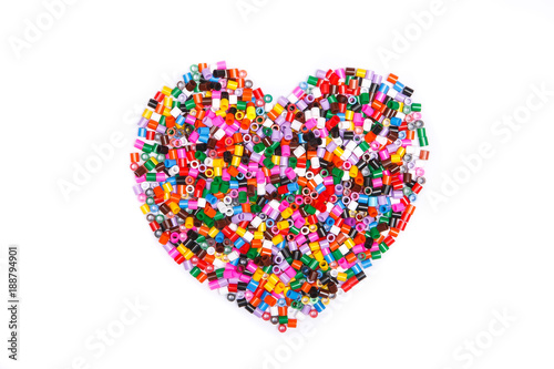 Frame in the shape of hearts. Background of multicolored decorative plastic craft beads. 