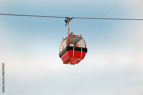 Fotografie Red gondola car lift on the ski resort against blue sky