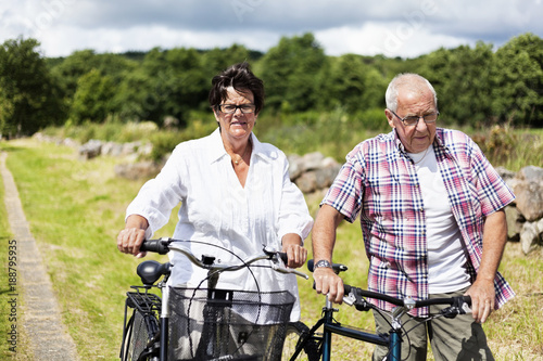 Senior couple walking with bicycles in countryside