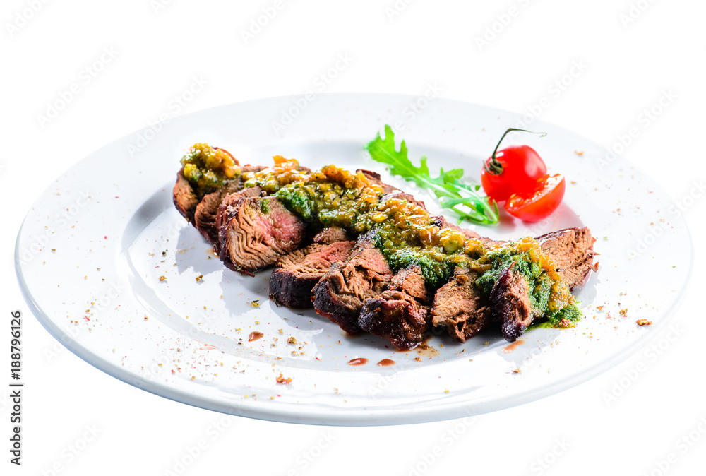 Juicy grilled beef steak with sauce pesto in a white plate, isolated on white background Juicy grilled beef steak with sauce pesto in a white plate, isolated on white background