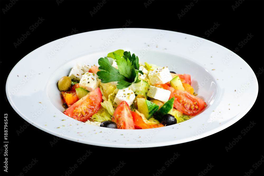 Greek salad with fresh vegetables, feta cheese and olives in a white plate isolated on black background Greek salad with fresh vegetables, feta cheese and olives in a white plate isolated on black background