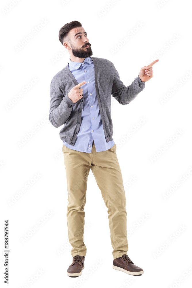 Uncertain confused bearded man pointing fingers up and looking above. Full body length portrait isolated on white studio background. Uncertain confused bearded man pointing fingers up and looking above. Full body length portrait isolated on white studio background.