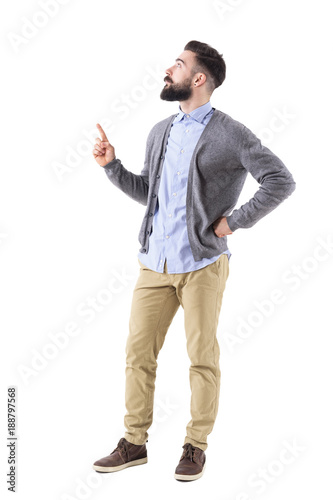 Confident stylish hipster business man pointing finger up and looking above. Full body length portrait isolated on white studio background. 