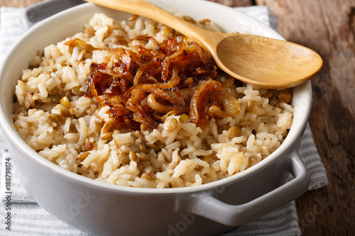 Stewed rice with lentils and fried onions close-up in a bowl. horizontal