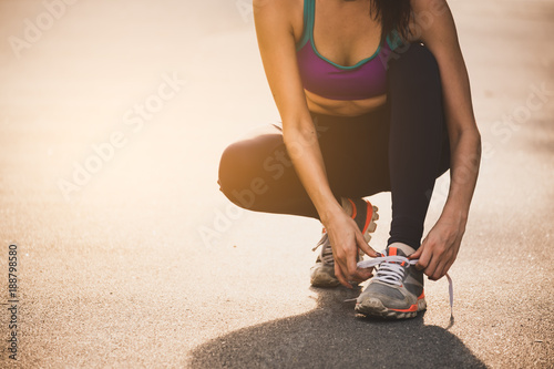 Athlete young woman sport runner tightening latching on running shoes/sneakers at track running stadium, sport running and fitness lifestyle concept