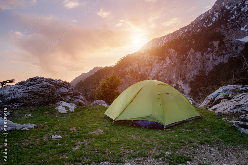 Green tent in the mountains at the sunset