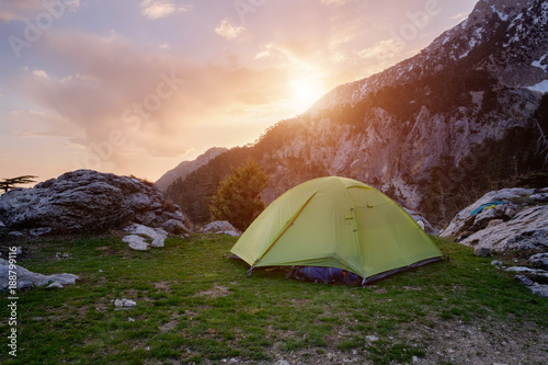 Green tent in the mountains at the sunset