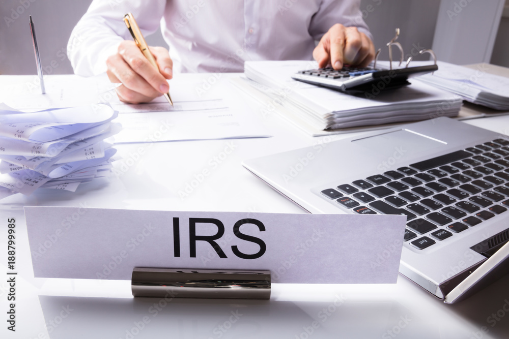 IRS Nameplate In Front Of Accountant Calculating Tax - obrazy, fototapety, plakaty 