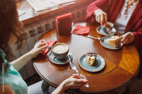Two women chatting in a coffee shop, cake on the table