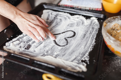 Cooking at home, hand draws a heart on flour