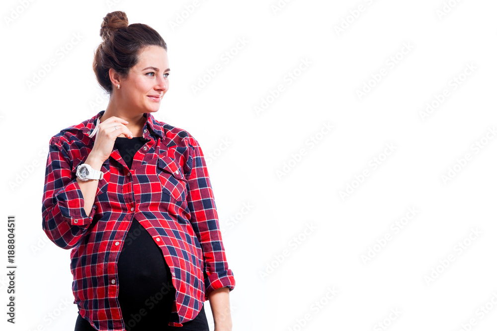Young dark-haired pregnant woman in black dress and plaid shirt smiling and posing on isolated white background Young dark-haired pregnant woman in black dress and plaid shirt smiling and posing on isolated white background