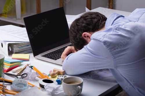 Foto Exhausted Businessman Resting On Messy Desk With Open Laptop