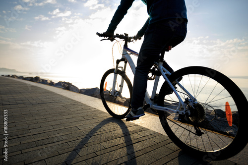 cyclist riding bike in the sunrise coast path