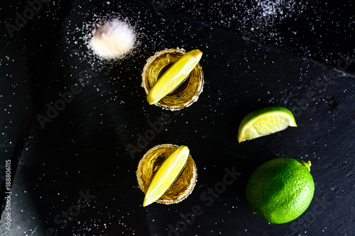Gold Mexican tequila with lime and salt on dark table. Top view, flat lay