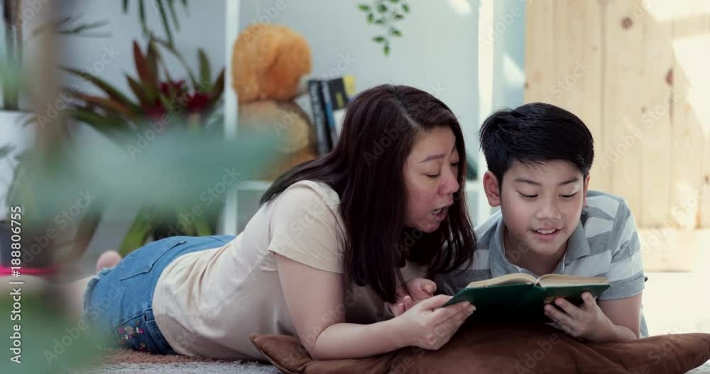 Happy asian family mother and son rest on floor and reading a book together. Happy asian family mother and son rest on floor and reading a book together.