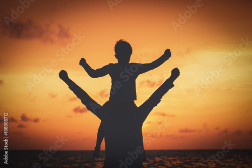 father and son play at sunset sky