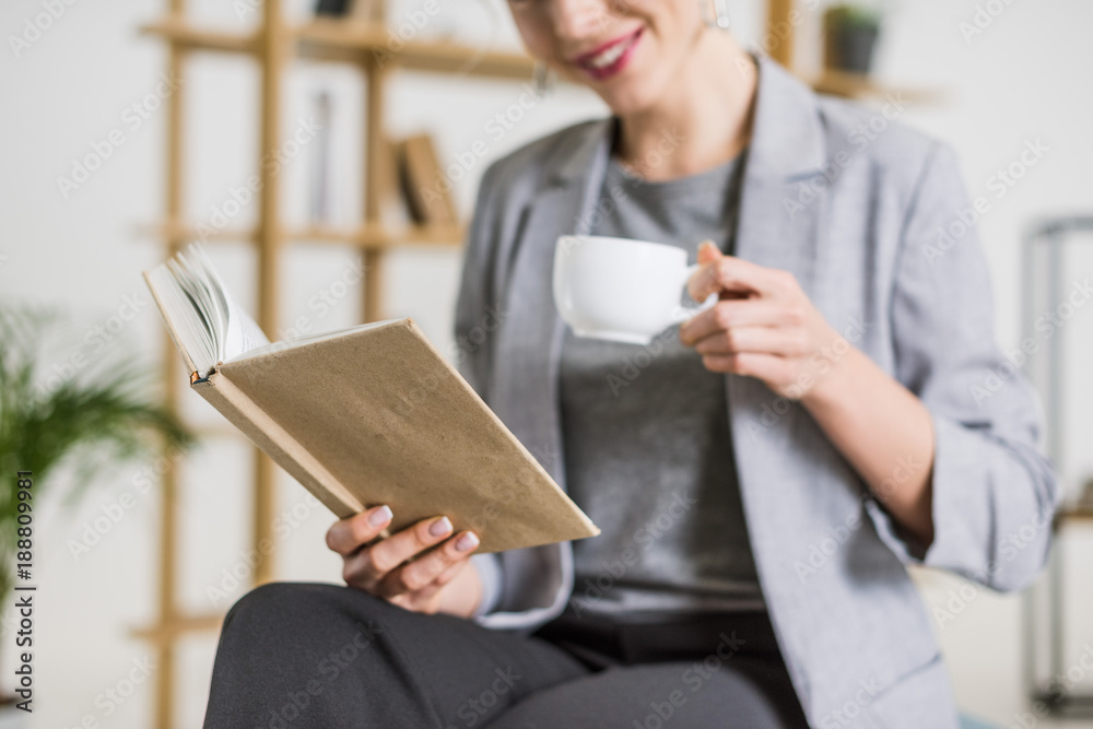cropped shot of smiling businesswoman with book and cup of coffee cropped shot of smiling businesswoman with book and cup of coffee
