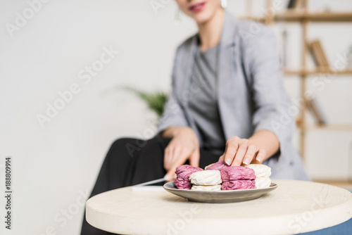selective focus of businesswoman taking zephyr from plate in office