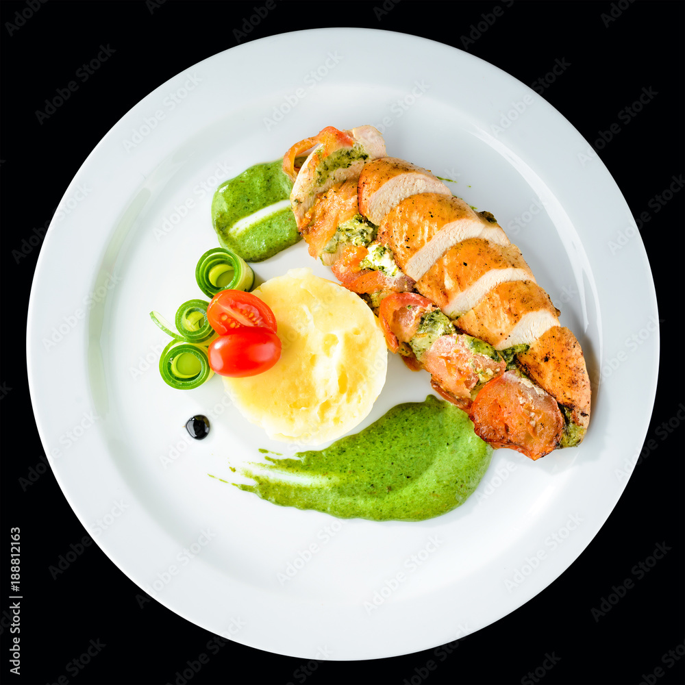 Grilled chicken fillet with pesto, spinach and sauce in a white plate. Top view, flat lay