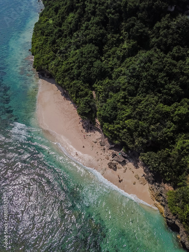 View of the island of Bali and the beach of Green Bowl. A small beach in the jungle. A long stone staircase leads to the beach. Top view from the drone.