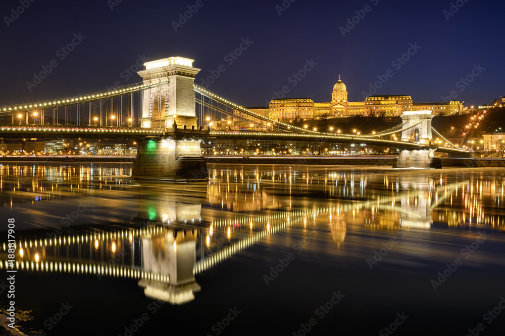 Szechenyi chain bridge against Buda Castle, moving ice floes on Danube river surface. Late night