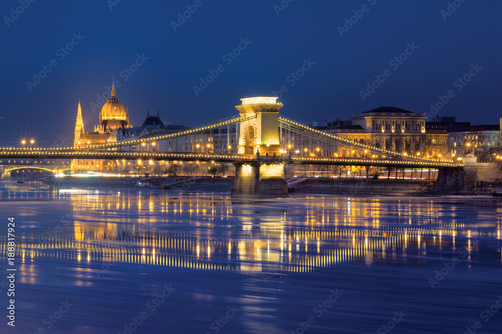 Szechenyi chain bridge reflected in blue Danube river waters, Parliament dome, Budapest