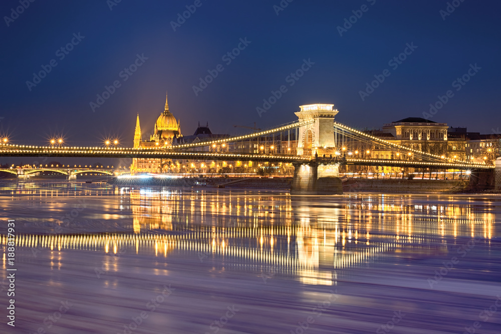 Szechenyi chain bridge reflected in Danube river water with floating ice trails, Budapest