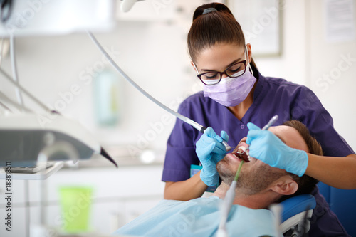 Fototapeta Naklejka Na Ścianę i Meble -  Young female dentist drilling tooth to patient