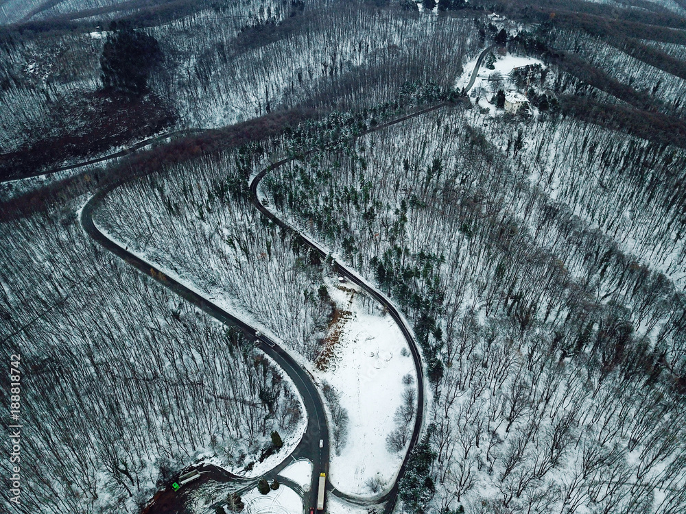 Snowy forest and road. Aerial view from a drone