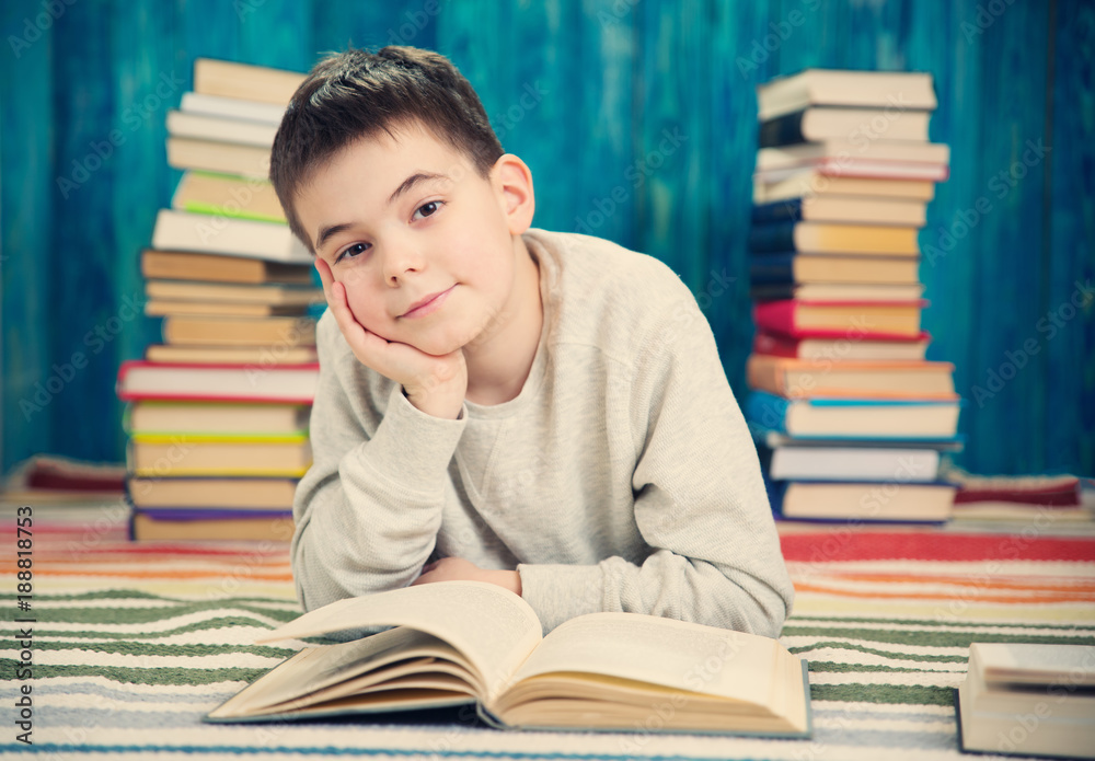 eight years old child reading a book at home. Boy studying at table on blue background eight years old child reading a book at home. Boy studying at table on blue background