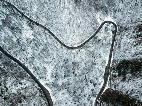 road in forest at early winter time. Aerial view from a drone looking down