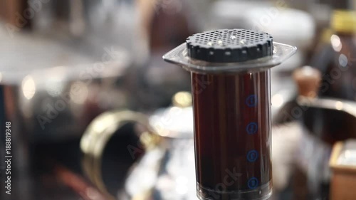 Barista make a cup of coffee, Aeropress model. Pouring hot water from teapot in aeropress pot with grounded coffee.