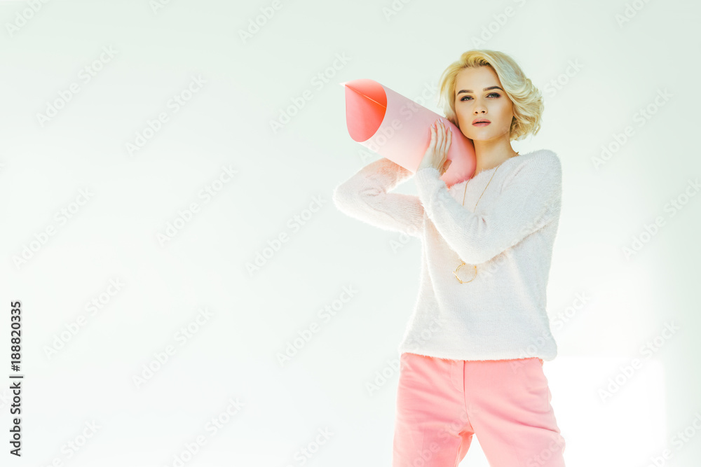fashionable young woman holding rolled pink paper and looking at camera on grey fashionable young woman holding rolled pink paper and looking at camera on grey