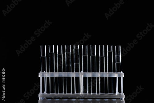 row of glass tubes with liquid on stand isolated on black