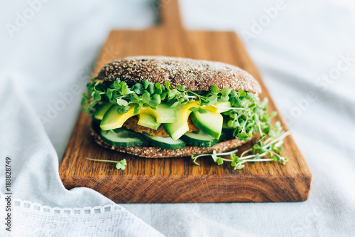 Vegetarian burger with cucumber, avocado, microgreen mustard on a wooden board